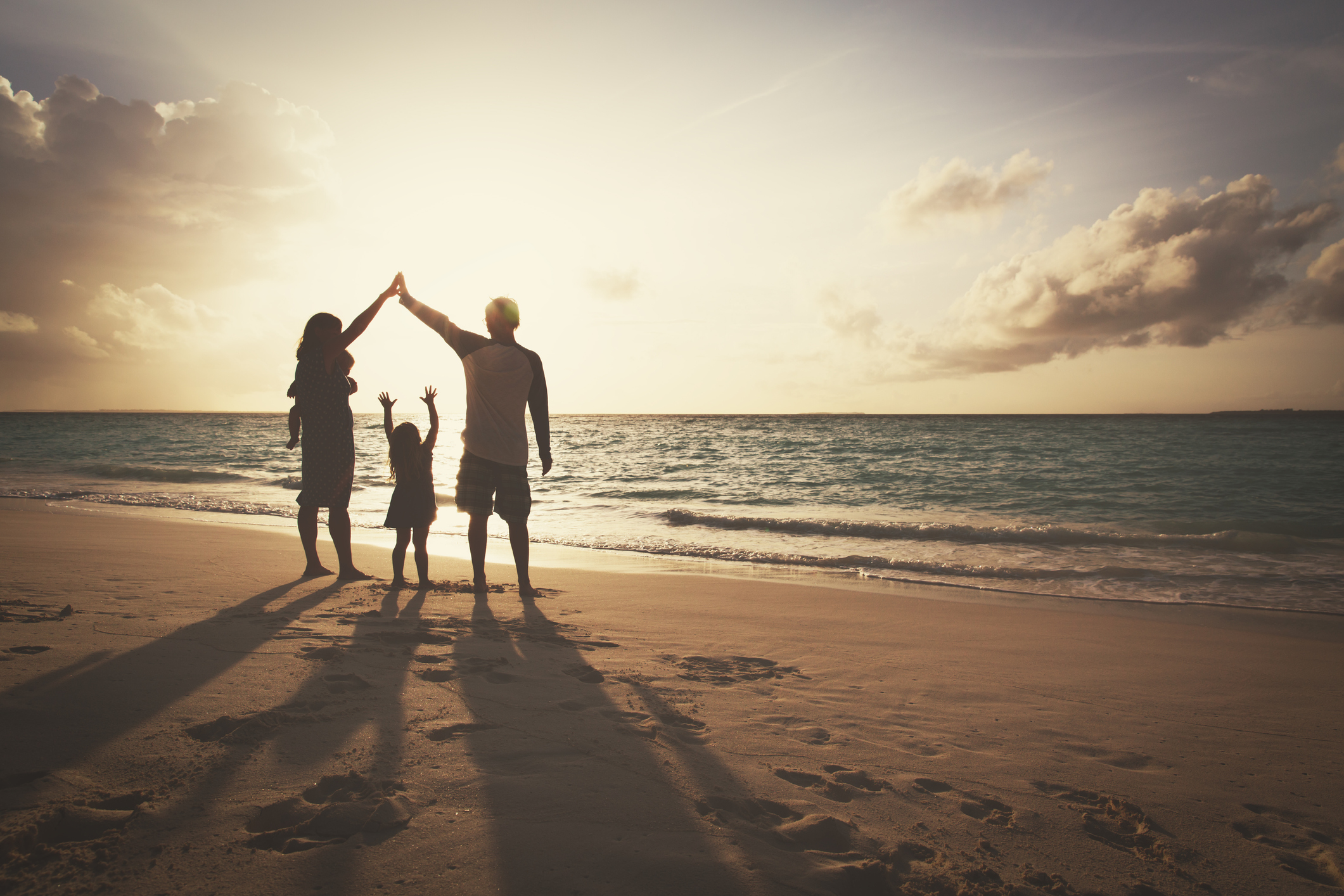 silhouette of family with two kids on play on sunset beach